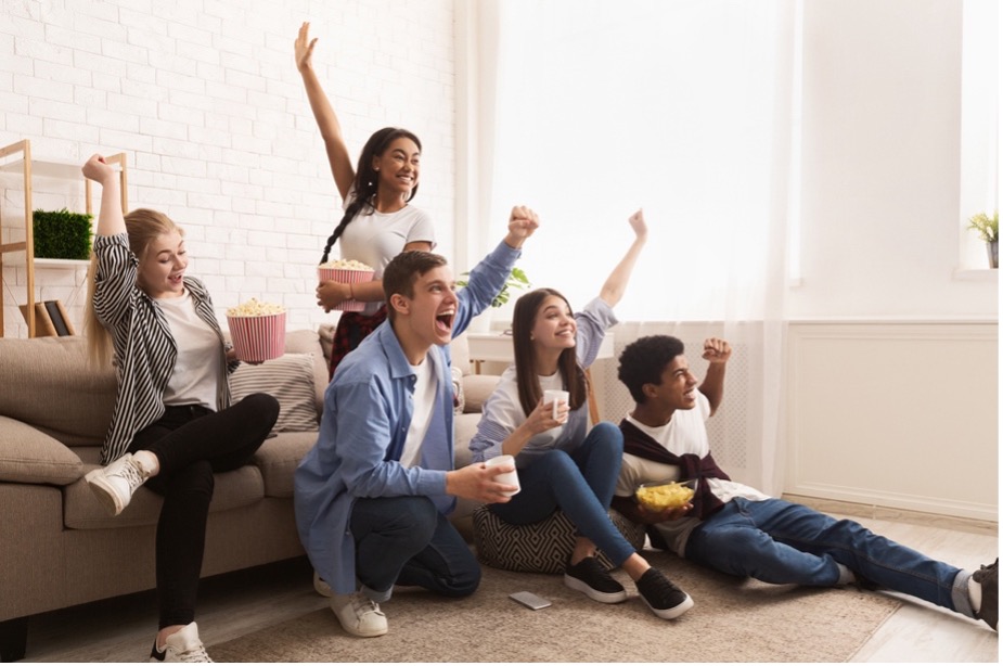 A group of people sitting on the floor with their hands up