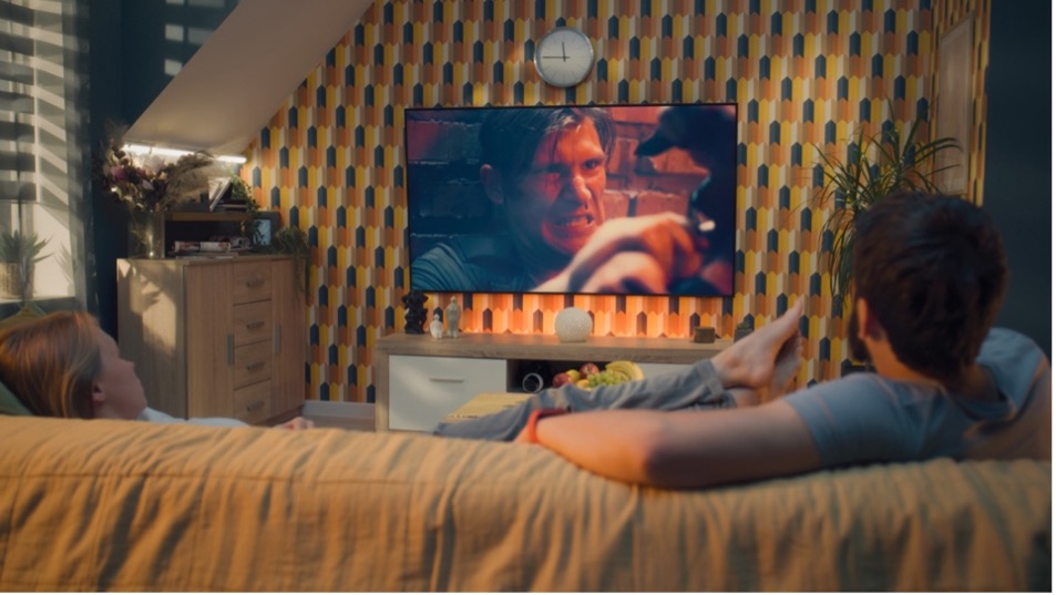 A person lying on a couch watching a movie