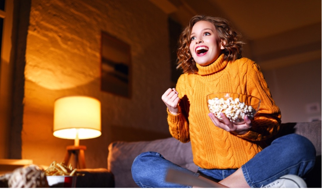 A person sitting on a couch holding a bowl of popcorn