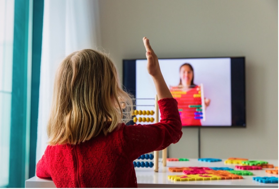 A child raising her hand in front of a television