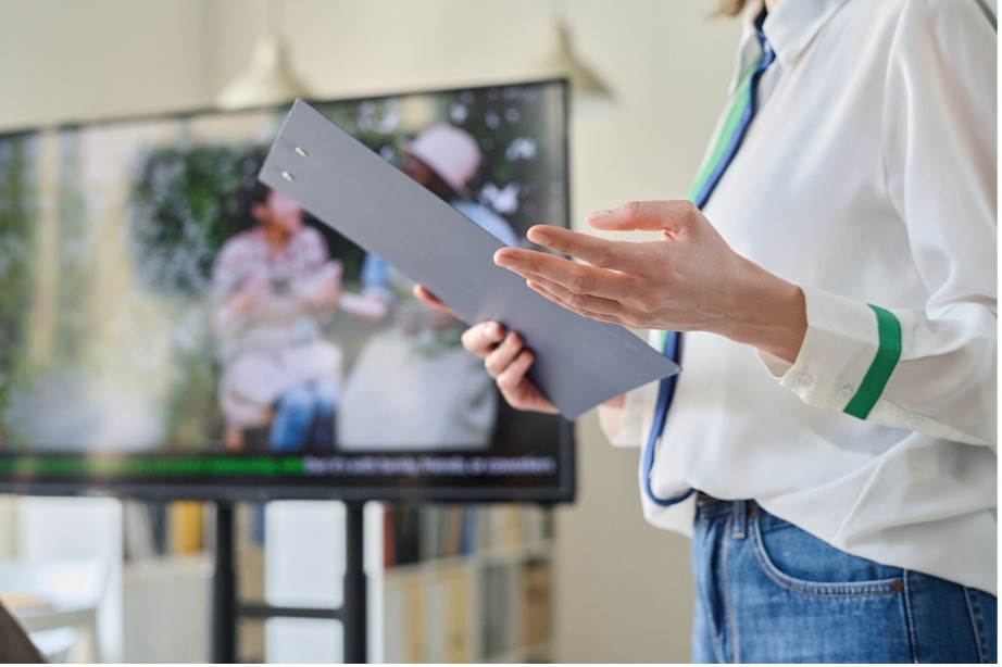 A person holding a clipboard in front of a television