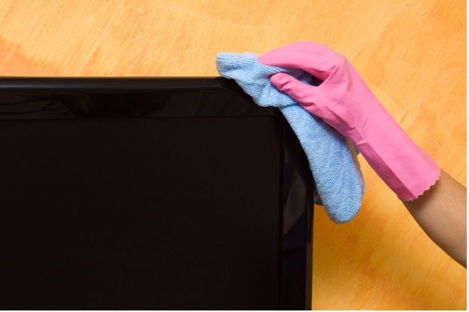 A gloved hand wiping a television